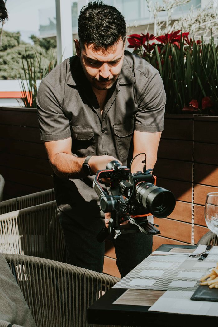 Professional photographer filming at an outdoor restaurant during the day.
