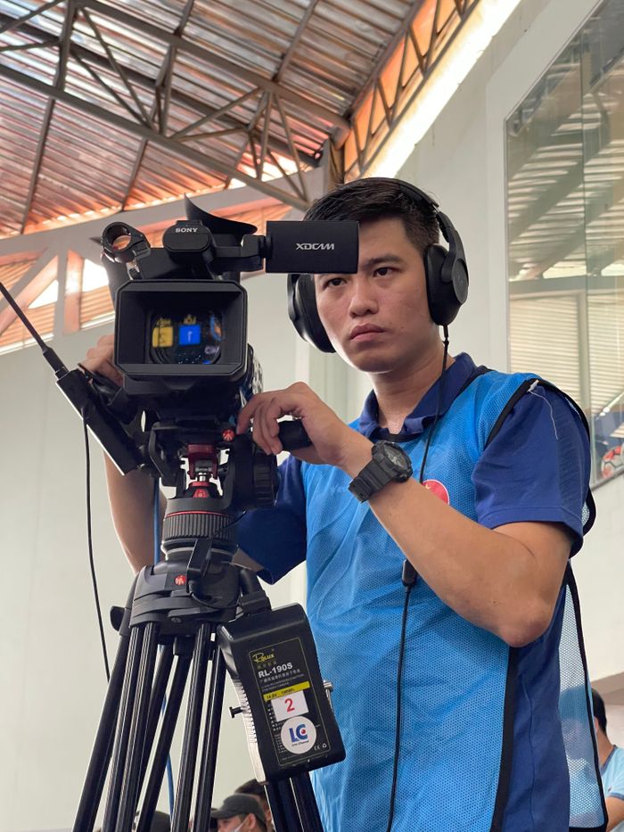 Crafting Captivating Headlines: Your awesome post title goes here A focused cameraman capturing footage at an indoor event with a professional video camera.