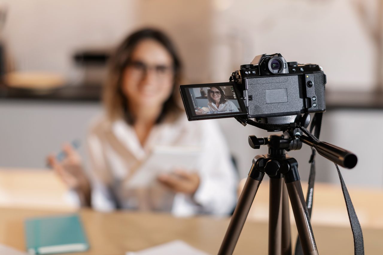 our-experience Woman vlogger using a camera and tripod for content creation indoors.